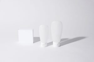 Two plain white sunscreen bottles on a pale background