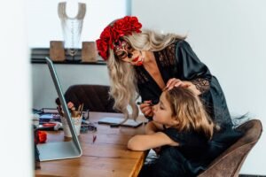 Woman in skull makeup painting a child's face, the moment to prep skin for Halloween makeup