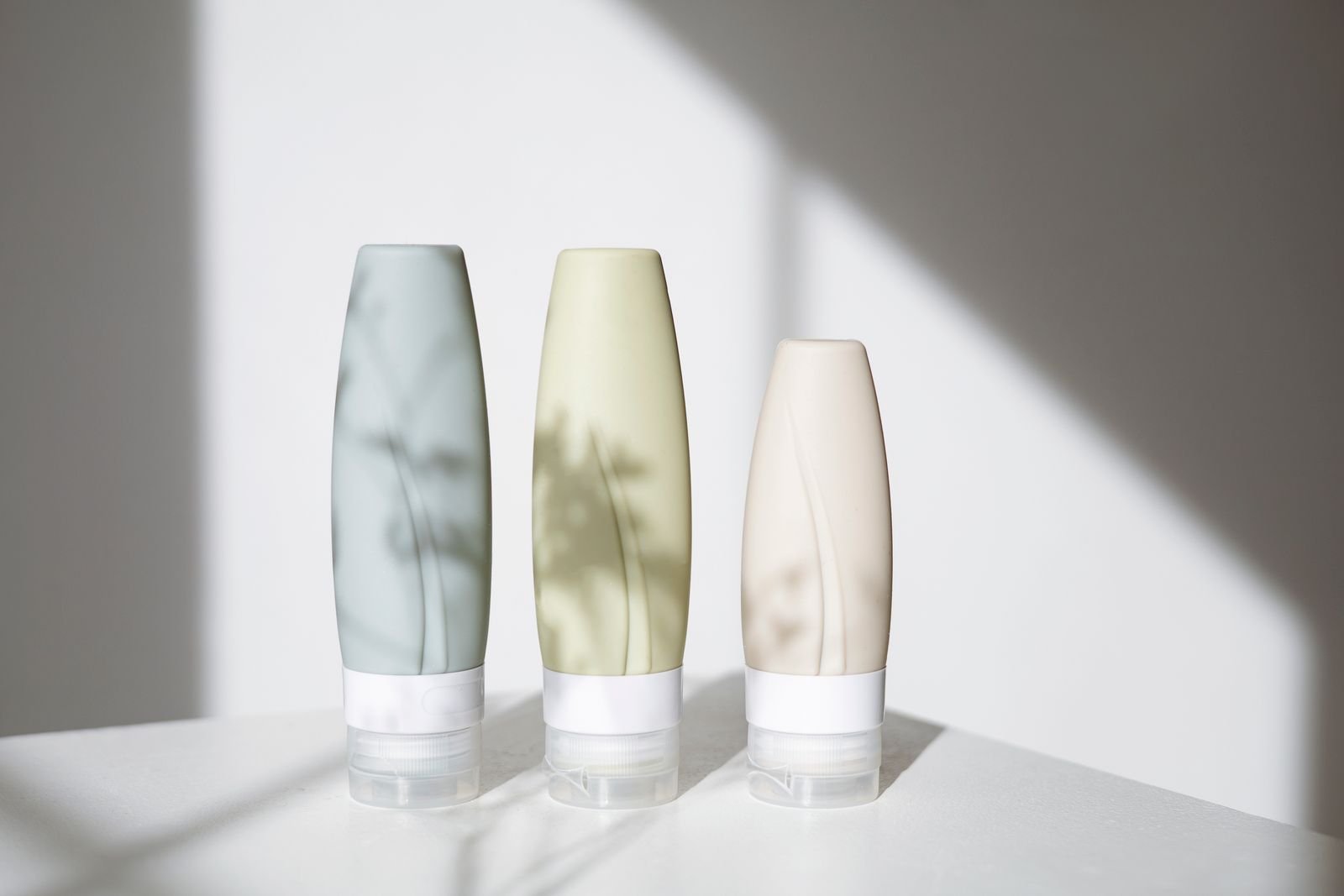 pexels-photo-8534231 - The Skincare Space Three unlabeled cleanser bottles standing on a white ledge in daylight