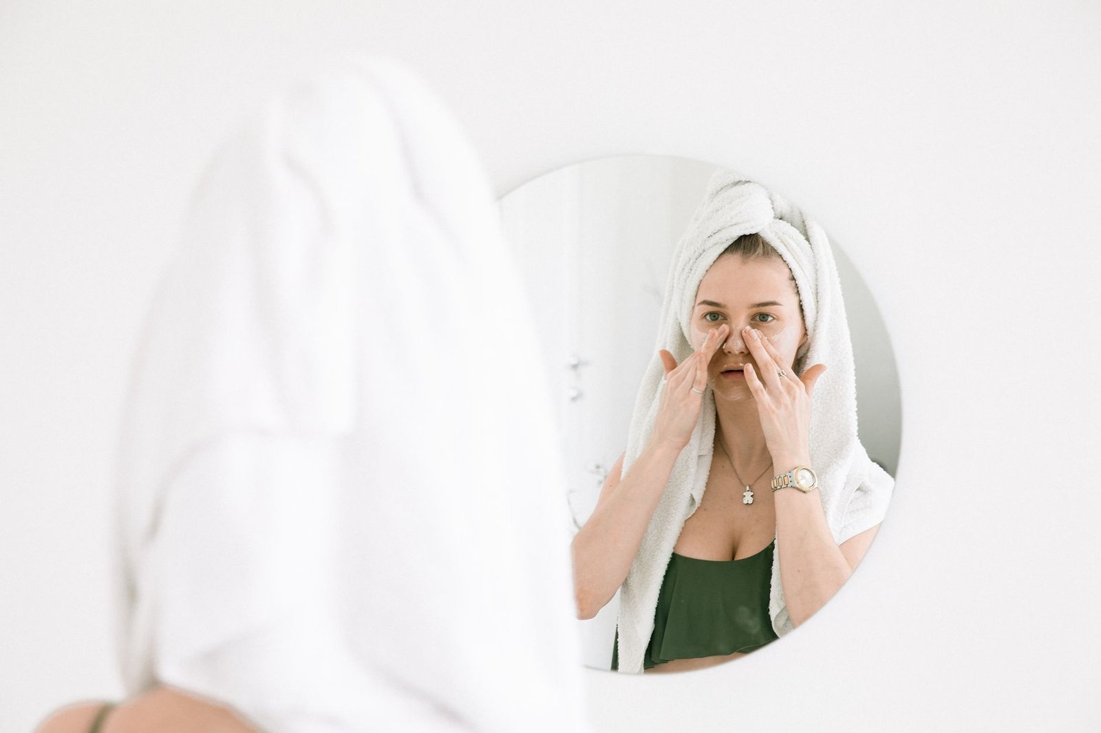 Skincare Routine for Beginners What You Need and What You Dont - The Skincare Space Person with a towel wrapped around their hair, hands raised to their face
